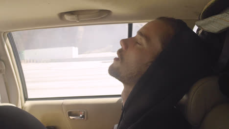 attractive young tired white man gen z millennial falls asleep in the back of car with mouth open during a road trip van life adventure in slow motion-1