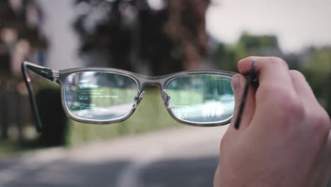 person holds augmented reality smart tech glasses in hand, futuristic hud shows code elements in lens