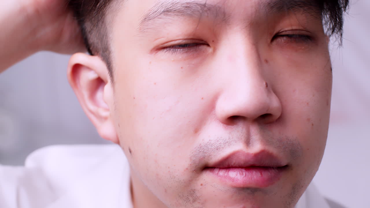 아시아 남자와 건강한 좋은 머리카락을 닫고 카메라를 보고 머리를 정리하여 자신을 망치고 있습니다.