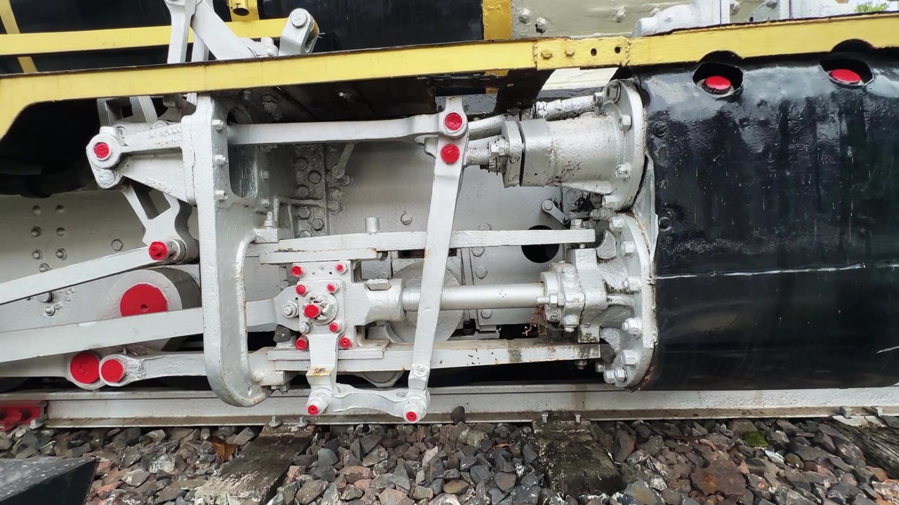 Tracking close up highlighting the drive mechanism and mechanical linkage of a preserved steam locomotive Editorial use only