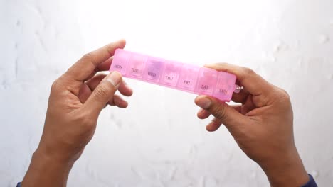 persona que sostiene un organizador de pastillas rosado