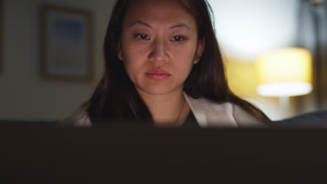 Close-Up-Of-Woman-Spending-Evening-At-Home-Sitting-On-Sofa-With-Laptop-Computer-Looking-At-Social-Media-Streaming-Or-Scrolling-Online