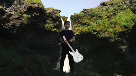 Man-playing-guitar-in-front-of-a-beautiful-waterfall-in-Iceland-24