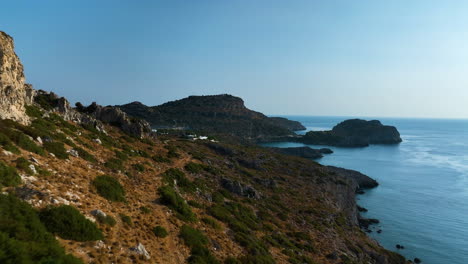 aerial view flying along the rocky coastline, revealing villas, sunrise in greece