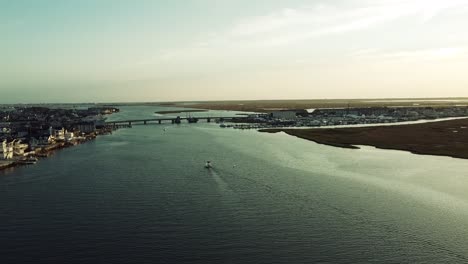 Ariel-Sobre-El-Puerto-Se-Dirigió-Hacia-El-Puente-En-Stoneharbor,-Nueva-Jersey-Con-Un-Pequeño-Bote-En-El-Centro-Durante-La-Hora-Dorada