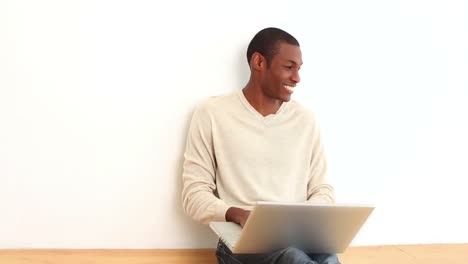 hombre feliz usando computadora portátil sentado en el suelo
