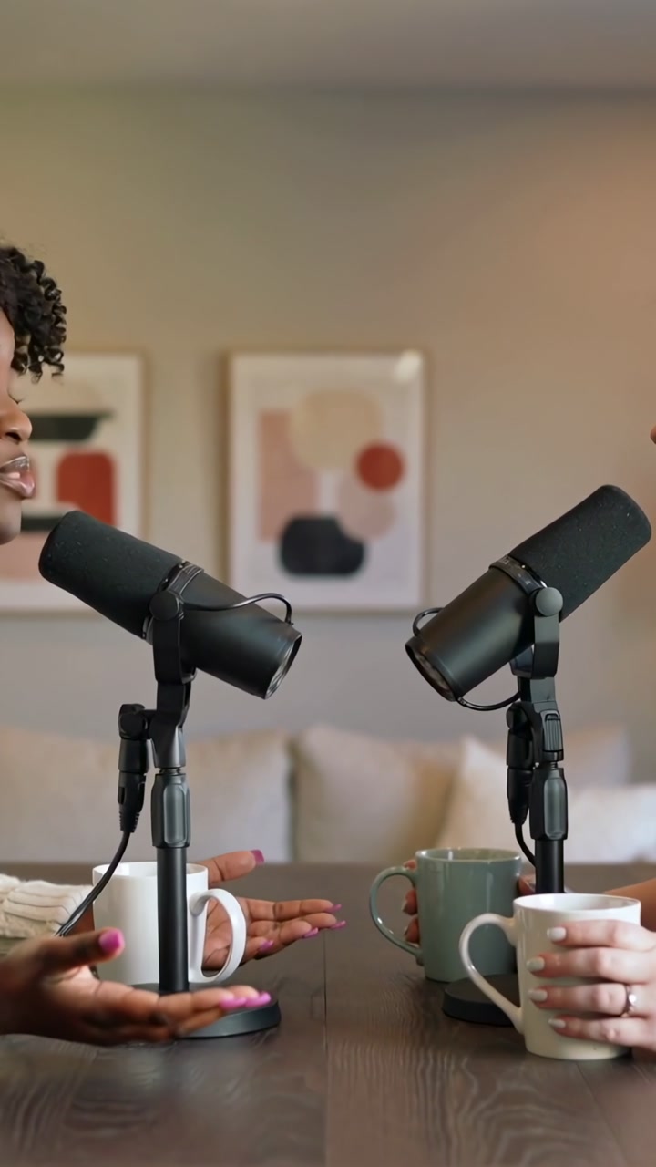 Vertical video: Starting talk, hosts speaking at studio table in sweater, mics for recording