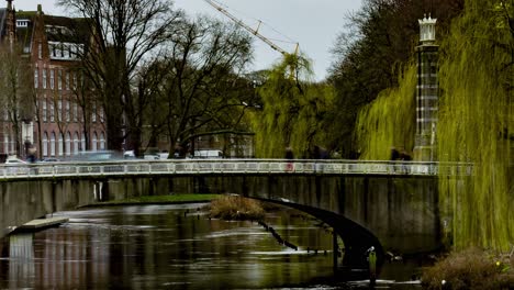 Wide-Time-lapse-Den-Bosch-city-center-with-people-and-cars-crossing-bridge-over-river---pan-right-to-left