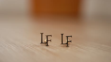 gold cufflinks featuring the initials "lf" on a wooden surface