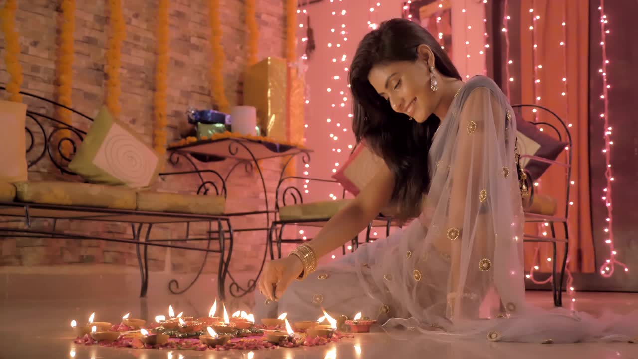 A beautiful girl in traditional sari making a Rangoli on a floor during Diwali festival.