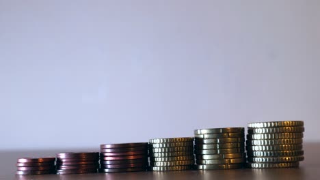 Close-up-shot-of-the-hands-picking-each-of-one-coin-from-the-pile-of-coins-or-money-arranged-in-growing-line,-Foreign-coins-saving-concept