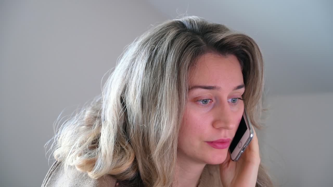 Close up of a woman with blonde hair talking on the phone