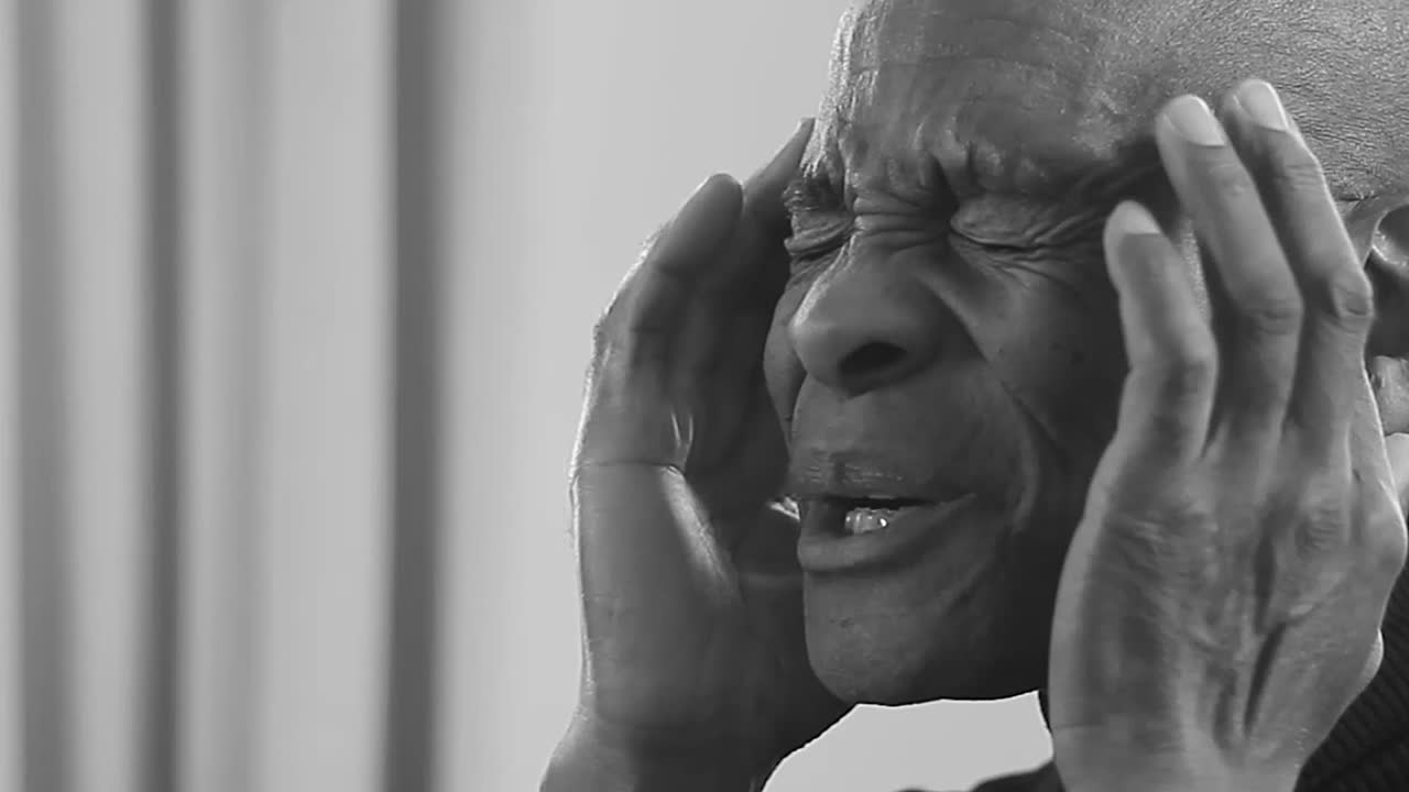 Vídeo de stock de un hombre con dolor de cabeza que se toca la cabeza sobre un fondo gris