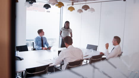 Businesswoman-Giving-Boardroom-Presentation-Viewed-Through-Meeting-Room-Window-Shot-In-Slow-Motion