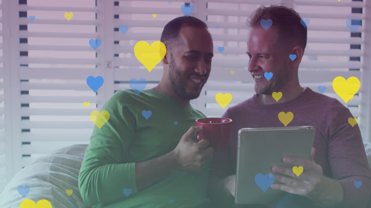 animación de corazones sobre una pareja gay diversa sonriendo y usando una tableta