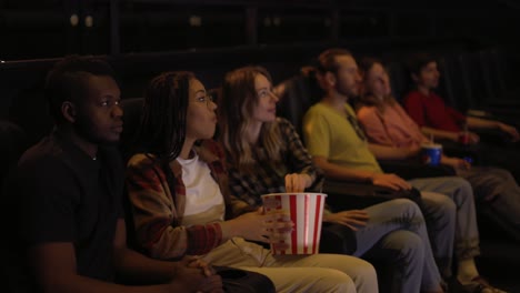 Group-of-diverse-young-friends-in-a-movie-theater,-came-watching-a-movie-on-a-big-screen