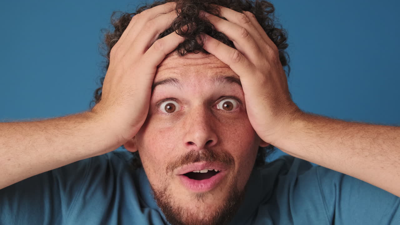 Man Reacts with Shock and Excitement, Hands on Head