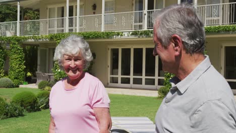 Portrait-of-happy-caucasian-senior-couple-smiling-in-garden-standing-in-the-sun