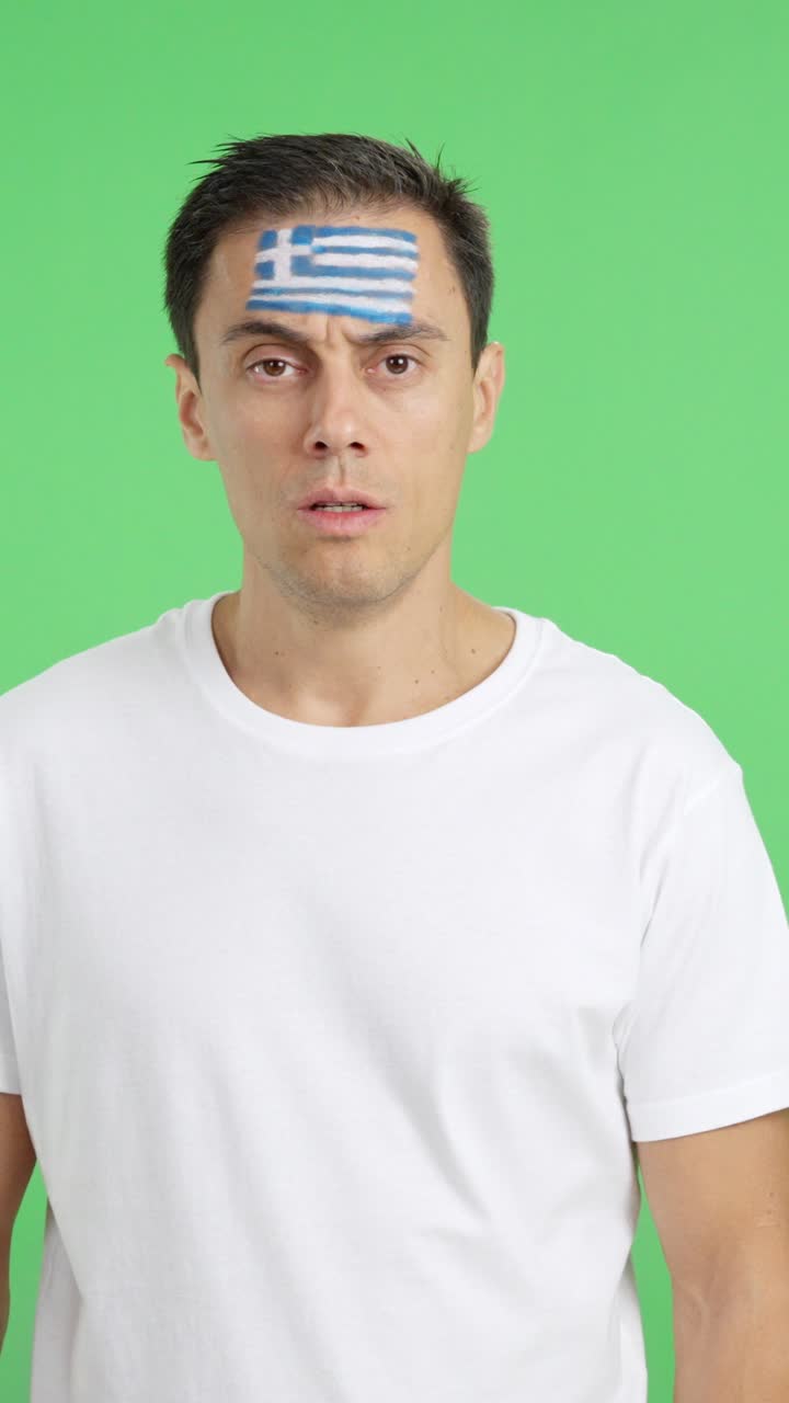 Man standing with greek flag painted on face smiling