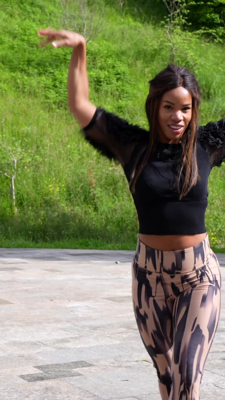 Woman dancing outdoors in leggings and a black top