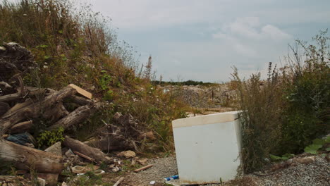 damaged refrigerator thrown out at landfill full of demolition waste piles