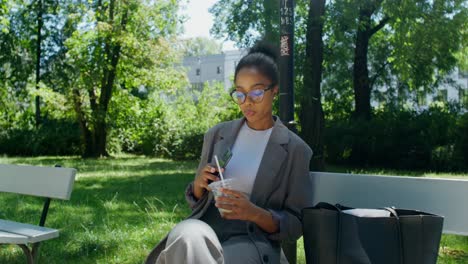 woman relaxing in park with coffee and phone