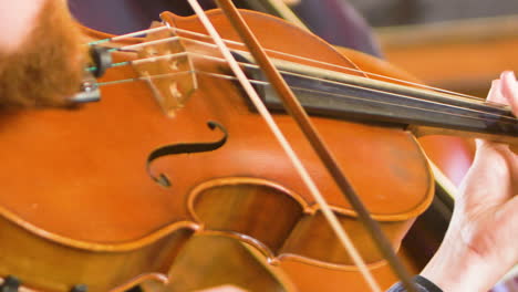 over the shoulder of a male viola player playing in a string quartet in a small, bright church