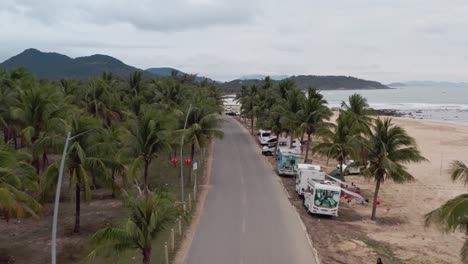 View-of-tropical-road-with-palm-trees-by-the-beach-side-with-parked-camper-vans-and-Recreation-vehicles