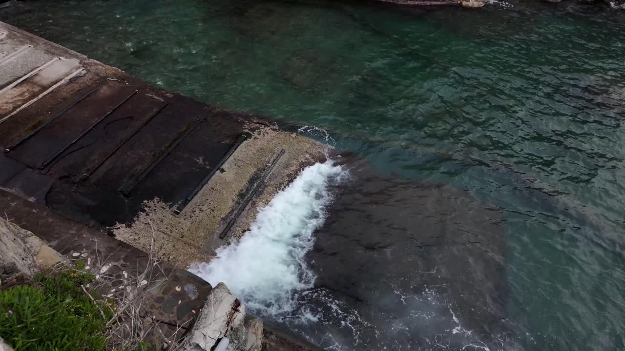 Slow motion of waves crashing against the stony dock in the village of Riomaggiore, Italy, capturing the raw power and tranquil beauty of this coastal scene