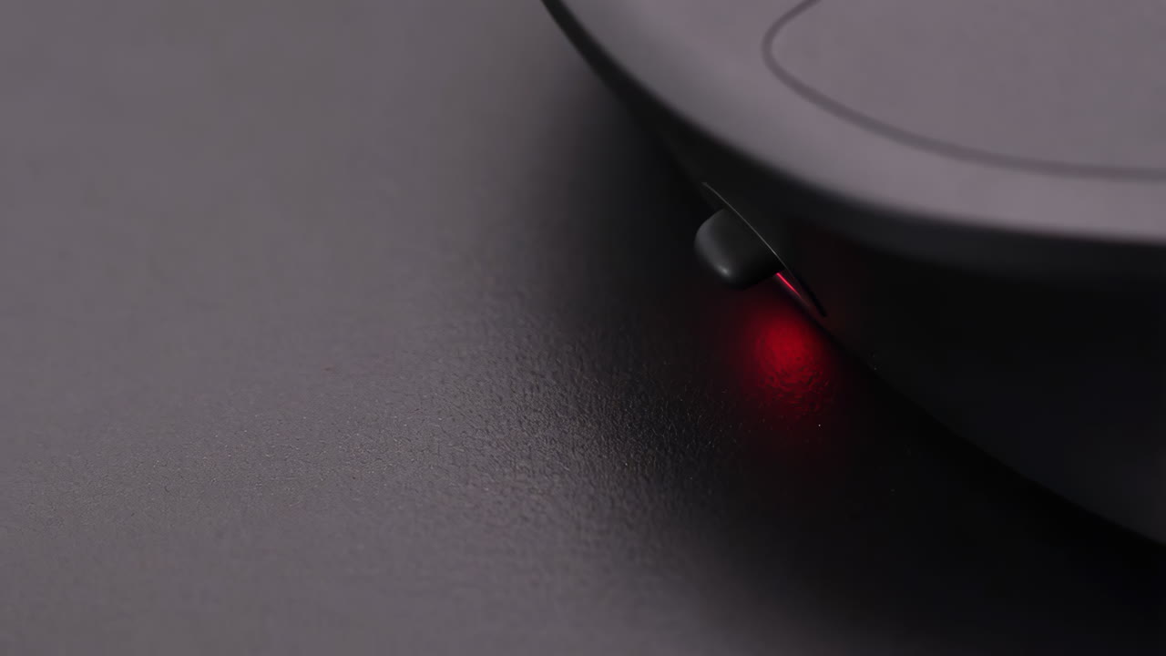 Close-up of a computer mouse with a red optical sensor light
