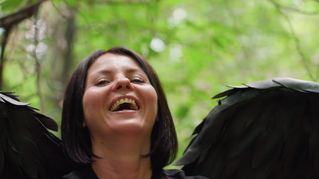 Black fairy with dark wings laughing joyfully in bright forest, face filled with happiness and light energy, symbolizing freedom, transformation, and playful spirit of fantasy mixed with mystery