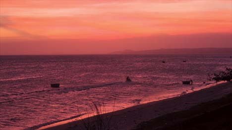 scenic sunset of jet ski in mui ne, vietnam, silhouetted against a red sunset over calm waters. the red skies fills the bay