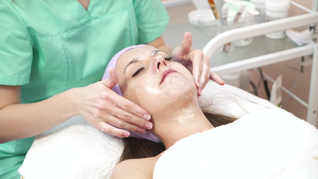 Facial massage by therapist. Lovely woman enjoying massage treatment by therapist in spa salon