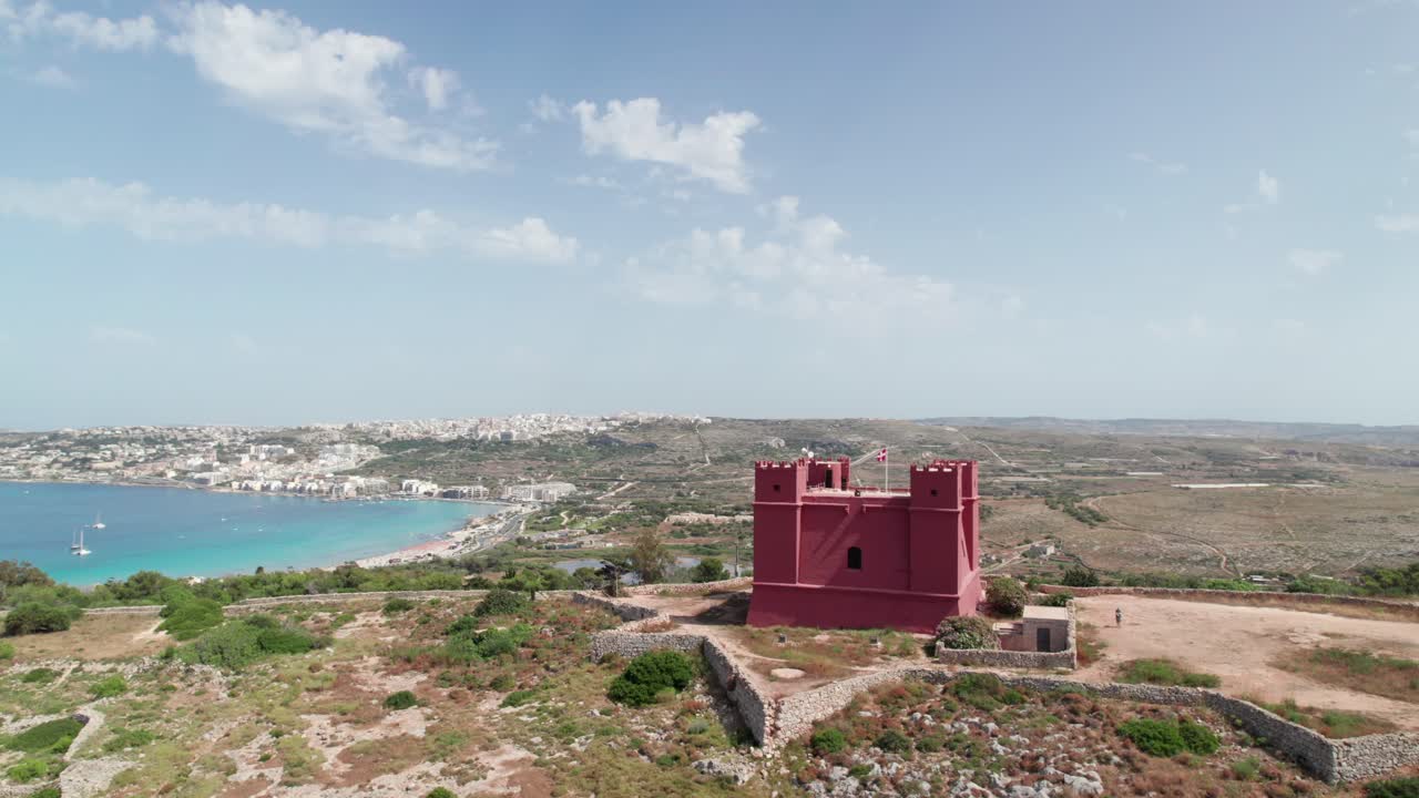 Red hilltop castle and Mediterranean landscape. Aerial view of Mellieha Tower in Malta