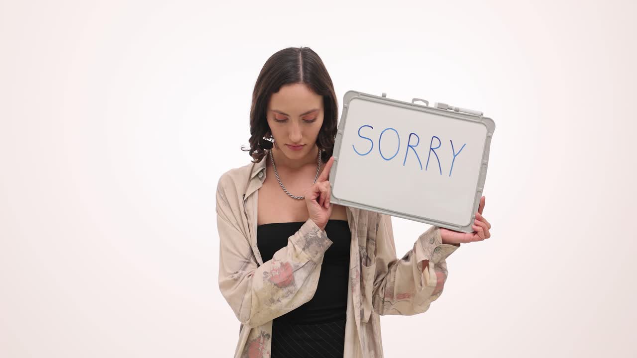 Woman holding a "SORRY" sign, expressing remorse and apology
