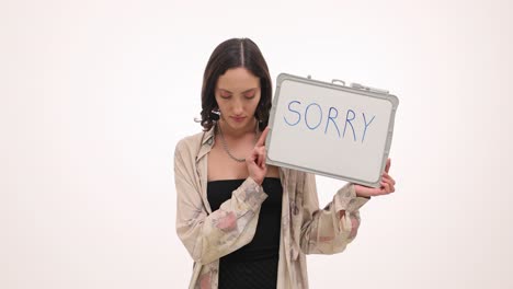 woman holding a "sorry" sign, expressing remorse and apology