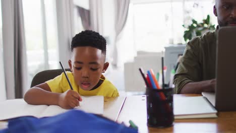 african american father and son doing homework and using a laptop together