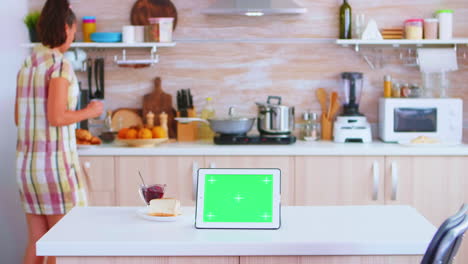 Woman-looking-at-tablet-computer-with-green-mockup