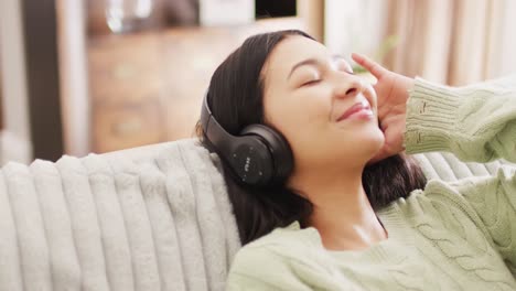 Video-of-smiling-biracial-woman-with-dark-hair-using-headphones-listening-to-music