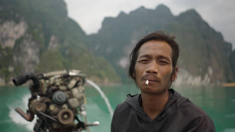 man smoking on a boat in a scenic mountain lake