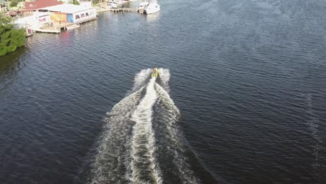 vuelo de drones a vista de pájaro detrás de un jetsky que viaja sobre el agua