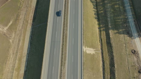 elevated shot of a highway with a singular car traveling down the road