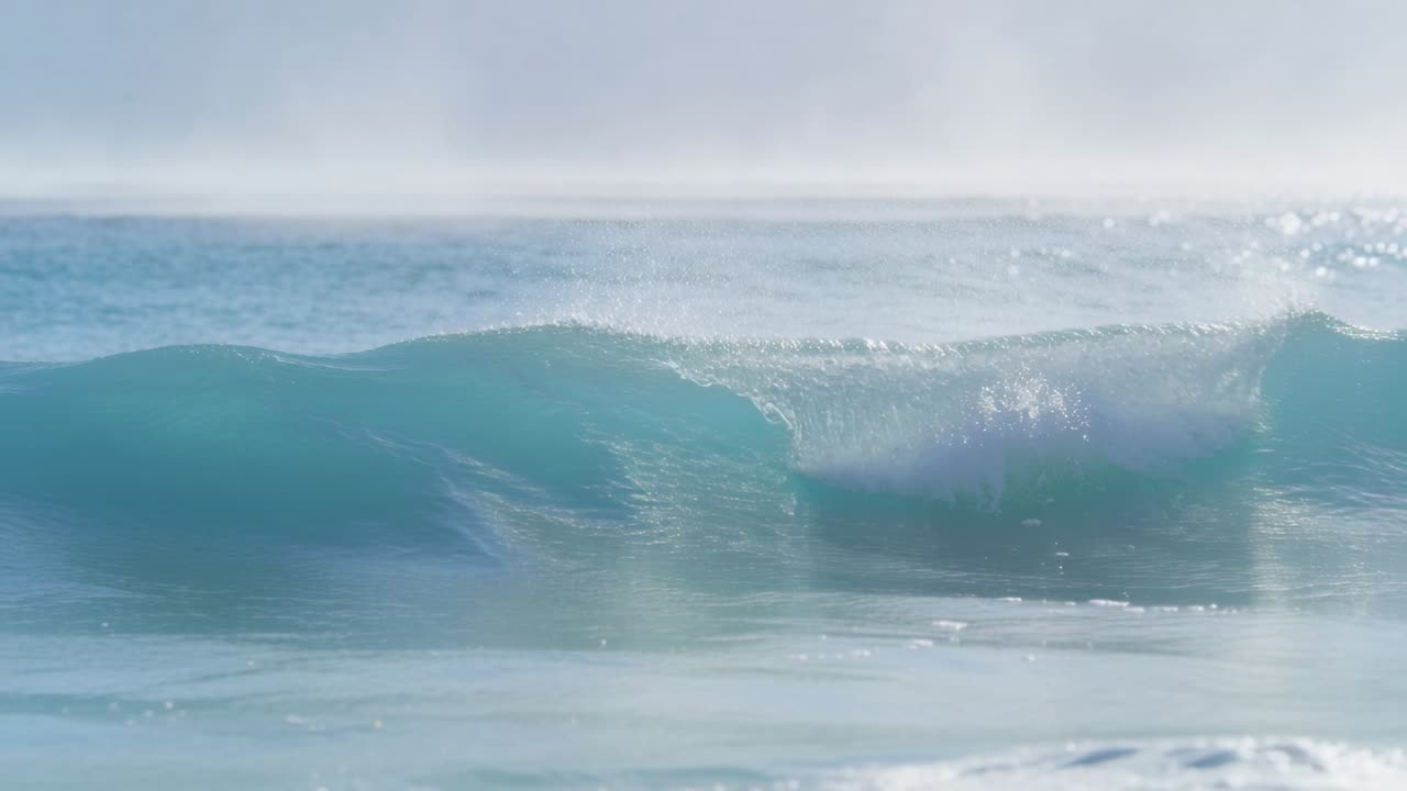 Breaking turquoise ocean wave forming curling lip and whitewater nearshore, with spray and horizon