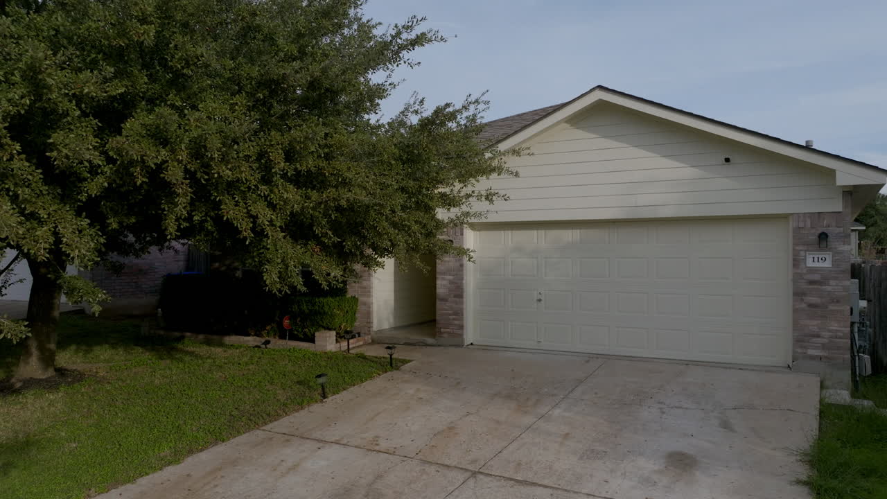carrinha aérea, casa suburbana branca e garagem com bela árvore de sombra no gramado