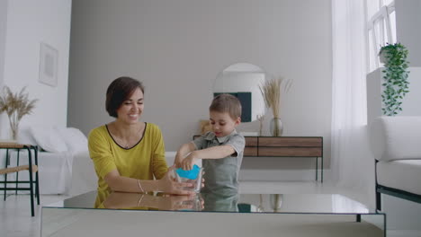 mom and son sitting on the floor playing at the table and laughing using an elastic toy.