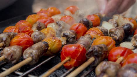 cinemagraph de humo emitido por cocinar corazones de pollo con tomate y cebolla en una parrilla de barbacoa caliente