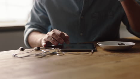 Joven-Empresario-Usando-Una-Tableta-En-Una-Cafetería-Tomando-Café-Navegando-En-Línea-Leyendo-El-Correo-Electrónico-En-Un-Dispositivo-Con-Pantalla-Táctil-De-Cerca