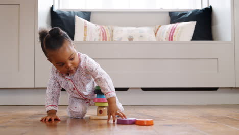 female toddler at home playing with wooden stacking toy