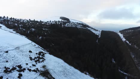 Snowy-Welsh-woodland-Moel-Famau-winter-landscape-aerial-view-rural-scene-pan-right