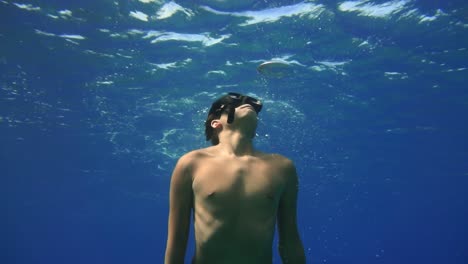 man follows air bubbles that rise to the surface as water glistens